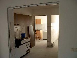 Bild: Die Kantine. Vorne befindet sich die Getränkeausgabe. Im Hintergrund links ist die Küche und im Raum rechts daneben das Lager für die Getränke.