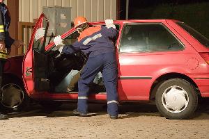 Bild: Ein Jugendfeuerwehrmann hat die Fahrertür des Unfallfahrzeugs geöffnet und erkundet die Lage im Fahrzeuginnenraum