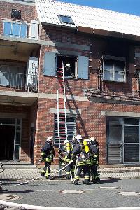 Bild: Einsatz über eine Steckleiter. Neben der schweren Schutzausrüstung muss auch der Schlauch mit Hohlstrahlrohr mitgenommen werden