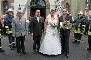 Bild: Löschbezirksführer Felix Becker (links) und Sascha Müller (rechts) gratulierten dem Brautpaar im Namen des Löschbezirks Eppelborn