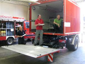 Bild: Das Abnahmeteam bei der Arbeit. Checkliste verlesen – Ausschreibevorgaben überprüfen oder nachmessen – Bestandsprotokoll schreiben. Allein die Überprüfung der feuerwehrtechnischen Beladung dauerte ca. fünf Stunden. Im Hintergrund steht ein TSF-W (Tragkraftspritzen-Fahrzeug mit Wassertank) für eine thüringische Feuerwehr in der Endfertigung