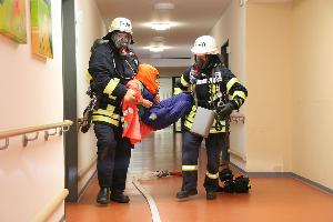 Bild: Mit einer Fluchthaube wird die Person vor den Rauchgasen geschützt und ins Freie gebracht