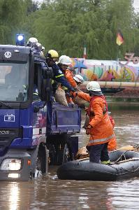 Bild: Bei der Sicherung eines notgedrungen im Blieshochwasser zurückgelassenen Autoscooters auf dem Wiebelskircher Festplatz arbeiten Feuerwehren aus Neunkirchen und Bildstock, das DLRG aus Eppelborn und Illingen sowie das THW aus Spiesen-Elversberg Hand in Hand zusammen. (Foto: Christopher Benkert - Feuerwehr Neunkirchen)
