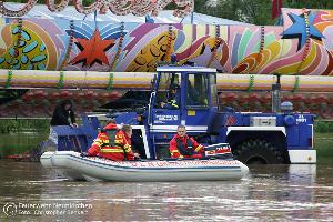 Bild: Bei der Sicherung eines notgedrungen im Blieshochwasser zurückgelassenen Autoscooters auf dem Wiebelskircher Festplatz arbeiten Feuerwehren aus Neunkirchen und Bildstock, das DLRG aus Eppelborn und Illingen sowie das THW aus Spiesen-Elversberg Hand in Hand zusammen. (Foto: Christopher Benkert - Feuerwehr Neunkirchen)