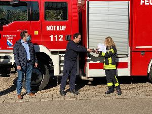 Bild: Löschbezirksführer Eric Holzer überreichten den Funkmeldeempfänger an Lara Müller